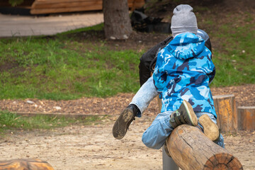 Children play on the playground with wooden logs.