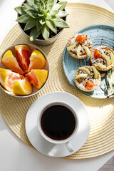 Coffee cup, tartlets and slices of grapefruits, breakfast in morning sunlight.