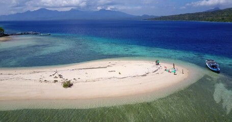Menjangan Island, bali, Indonesia. Aerial drone view. Slow low level flight across a sand tongue showing the coastline, the coral reef and a diver's boat.