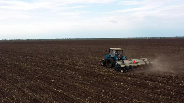 Tractor with Plough on Plowed. Ploughing and Soil Tillage. Agricultural Tractor on Cultivation Field for Sowing Seeds. Tractor During Field Cultivating. Planting and Seeding Equipment.