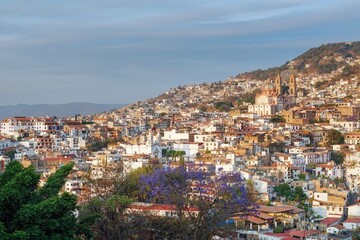 Colonial city on a mountainside before sunset. The architecture is illuminated by the rays of the sun. Evening sky. The cramped streets of Taxco in Mexico