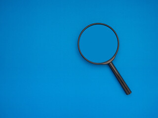Search concept. A magnifying glass on a blue background with copy space for text