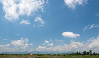 The white clouds have a strange shape and country side.Cloudy and blue sky.