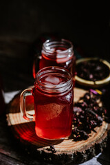 Agua de Jamaica or roselle mocktail drink, summer beverage in mexico with ice and dry hibiscus petals on table background