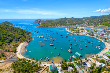 Vinh Hy Bay viewed from above at noon in summer with hundreds of fishing boats moored and fishing villages below. This is a beautiful bay to visit in Ninh Thuan, Vietnam