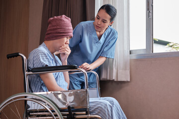 Uniformed young Asian female therapy doctor with wheelchair male patient at window to support...