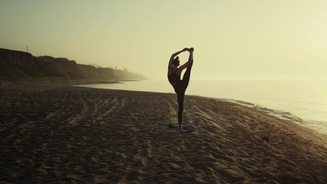 Unknown girl standing twine on sandy beach. Flexible woman doing stretching.