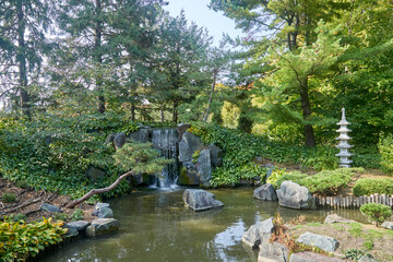 Fototapeta na wymiar Beautiful garden with pond, waterfall, rocks, plants in a serene setting