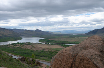 The valley of the river under an overcast cloudy sky. View of the river from a height.