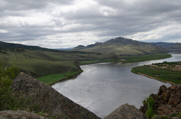 The valley of the river under an overcast cloudy sky. View of the river from a height.