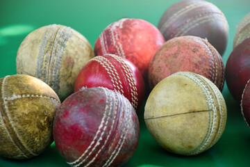 Closeup old and used leather cricket balls on green floor, soft and selective focus. concept for cricket lover around the world.