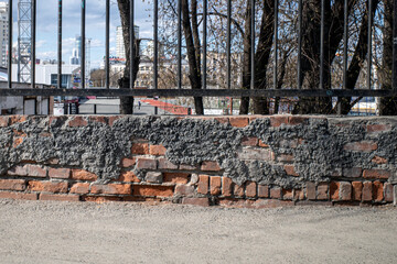 A fragment of the basement of an old metal fence on a spring day