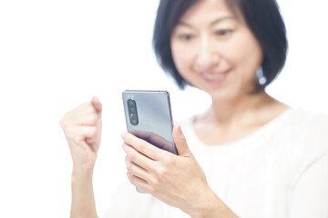 スマホを持ちガッツポーズする中年女性
