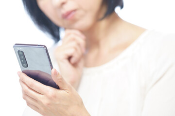スマホを見て顎に手をあて首をかしげる中年女性