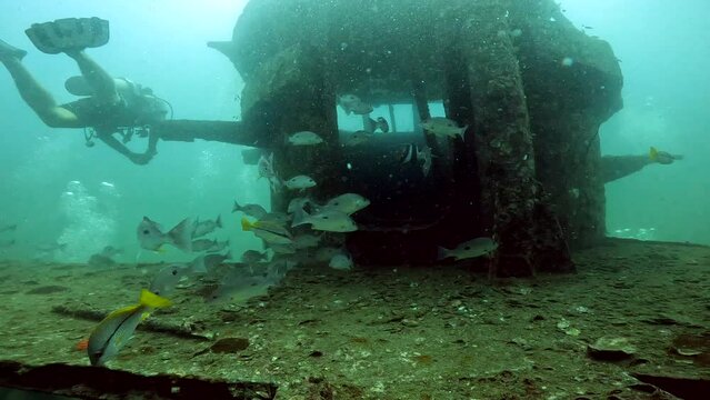 Under water scuba diving film - Diving around the bridge of the HTMS Sattakut wreck at 36 meters depth - some tropical fish and dviers in the scene -Southern Thailand