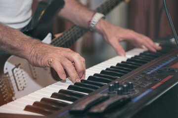 Obraz premium Man playing piano on dramatic dark stage on blurred guitar player background.