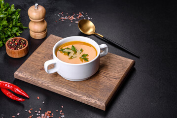 Delicious fresh pumpkin puree soup decorated with parsley in a white plate