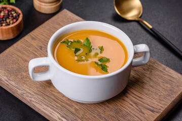 Delicious fresh pumpkin puree soup decorated with parsley in a white plate
