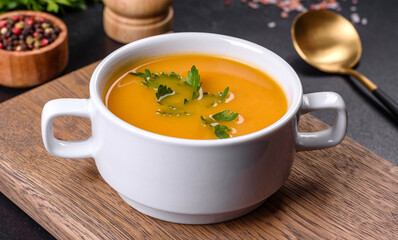 Delicious fresh pumpkin puree soup decorated with parsley in a white plate
