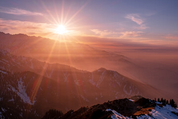 Magical atmosphere of a sunset in the highlands; sunset sky over snow-capped mountain ridges