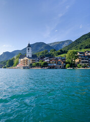 Fototapeta premium St. Wolfgang, Austria - August 16, 2019: Beautiful view from the lake to the architecture of the city of St. Wolfgang against the backdrop of the Alps. Church of St. Wolfgang is the main attraction