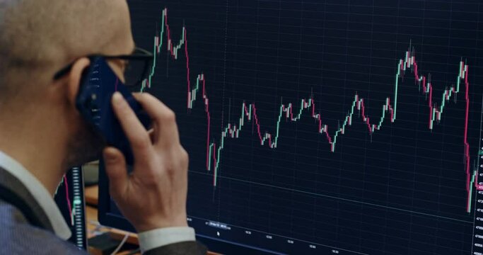 Employee answers phone call checking international stock market data on wall computer screen in office closeup. Communication to get good deal