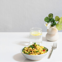 Vegetarian salad  with bulgur and vegetabls served with  glass of water on on the restaurant table.