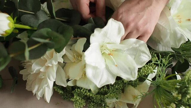 Making artificial flower arrangement with white flowers, zip tie and wire cutters, close up