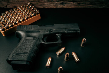 A black 9mm pistol on a black background with a box of 9mm ammunition next to it. top view