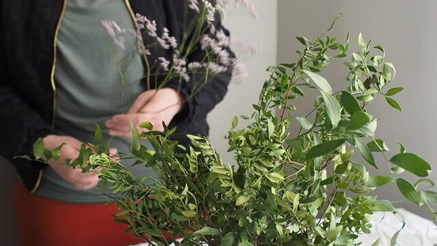 Arranging flowers and adding sea lavender flowers to flower arrangement, close up 