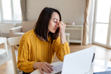 Frustrated woman working from home office in front of laptop suffering from chronic daily headaches, treatment online, appointing to a medical consultation, electromagnetic radiation, sick pay