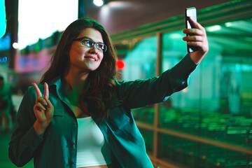 Girl takes selfie in front of shopping center. Communication and social media concept.