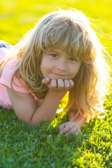 Summer child face. Smiling child boy with grass background. Summer kids outdoor portrait. Happy child enjoying on grass field and dreaming. Kids on green grass background.