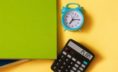 Word plan on a calculator on a yellow background with a folder for documents and a clock