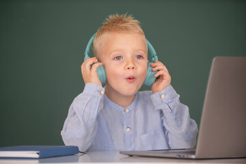 Smart boy in headphones sit at desk, study online on laptop at school, klever kid wear earphones in notebook learning using internet lessons. First day at school.