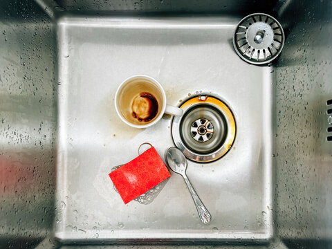 Sponge, coffee cup and a tea spoon in kitchen sink