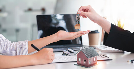 Close-up shot of a real estate agent or realtor meeting with her client, giving house key and new...