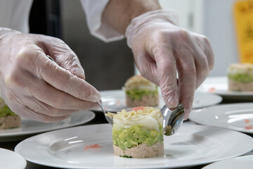 chef plating food only hand showing in low light with grain and out of focus