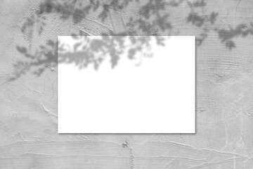 Empty white horizontal rectangular poster mockup with light shadow on gray concrete wall background.