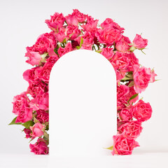 Spring pink flowers - roses as framing of arch on abstract white stage mockup for showing of...