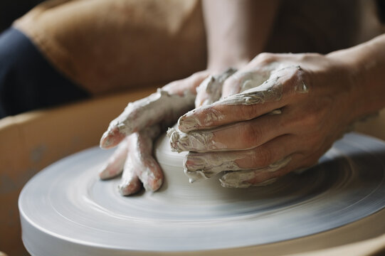 Potter's hands molding clay bowl on pottery wheel, ceramic art class, close up hands and raw clay