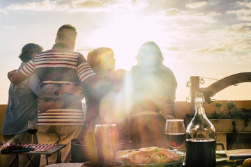 Back view of mature people hugging in friendship agains a wonderful sunset with sun flare. Food and...