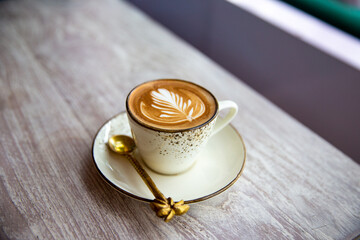 Hot cappuccino coffee cup with heart shape latte art on brown old wooden table at cafe.