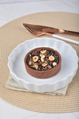 luxury home baked rocher dark rich chocolate tart in 3 layer with hazelnut mixed nuts and gold foil in white background halal dessert menu for hotel cafe