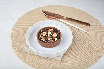 luxury home baked rocher dark rich chocolate tart in 3 layer with hazelnut mixed nuts and gold foil in white background halal dessert menu for hotel cafe