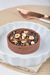 luxury home baked rocher dark rich chocolate tart in 3 layer with hazelnut mixed nuts and gold foil in white background halal dessert menu for hotel cafe