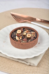 luxury home baked rocher dark rich chocolate tart in 3 layer with hazelnut mixed nuts and gold foil in white background halal dessert menu for hotel cafe