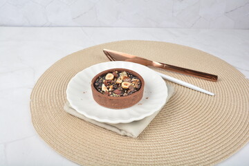 luxury home baked rocher dark rich chocolate tart in 3 layer with hazelnut mixed nuts and gold foil in white background halal dessert menu for hotel cafe