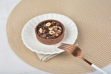 luxury home baked rocher dark rich chocolate tart in 3 layer with hazelnut mixed nuts and gold foil in white background halal dessert menu for hotel cafe