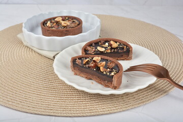 luxury home baked rocher dark rich chocolate tart in 3 layer with hazelnut mixed nuts and gold foil in white background halal dessert menu for hotel cafe